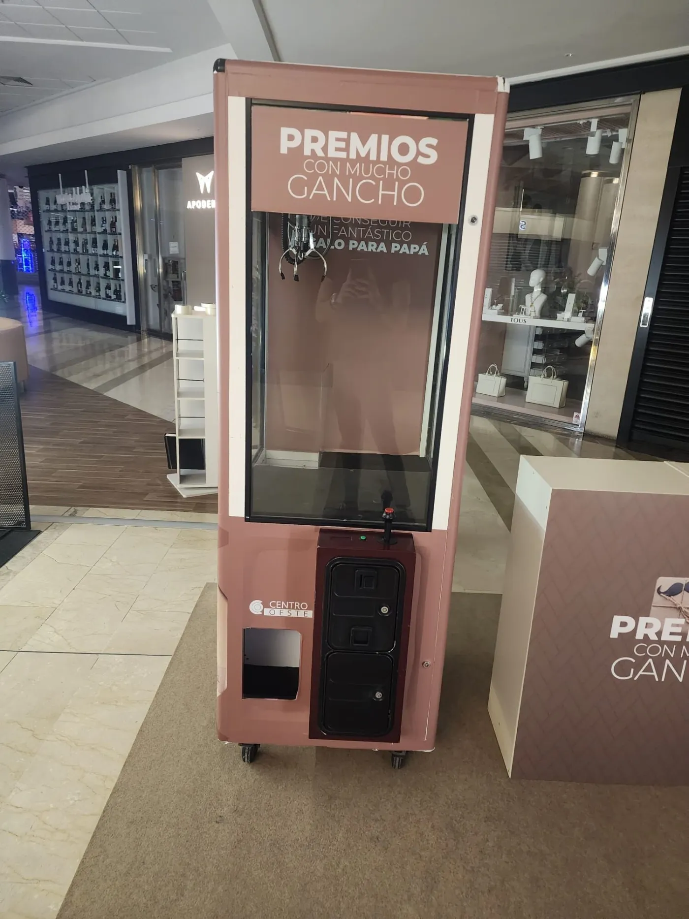 Máquina de gancho vinilada en un centro comercial con el lema Premios con mucho gancho